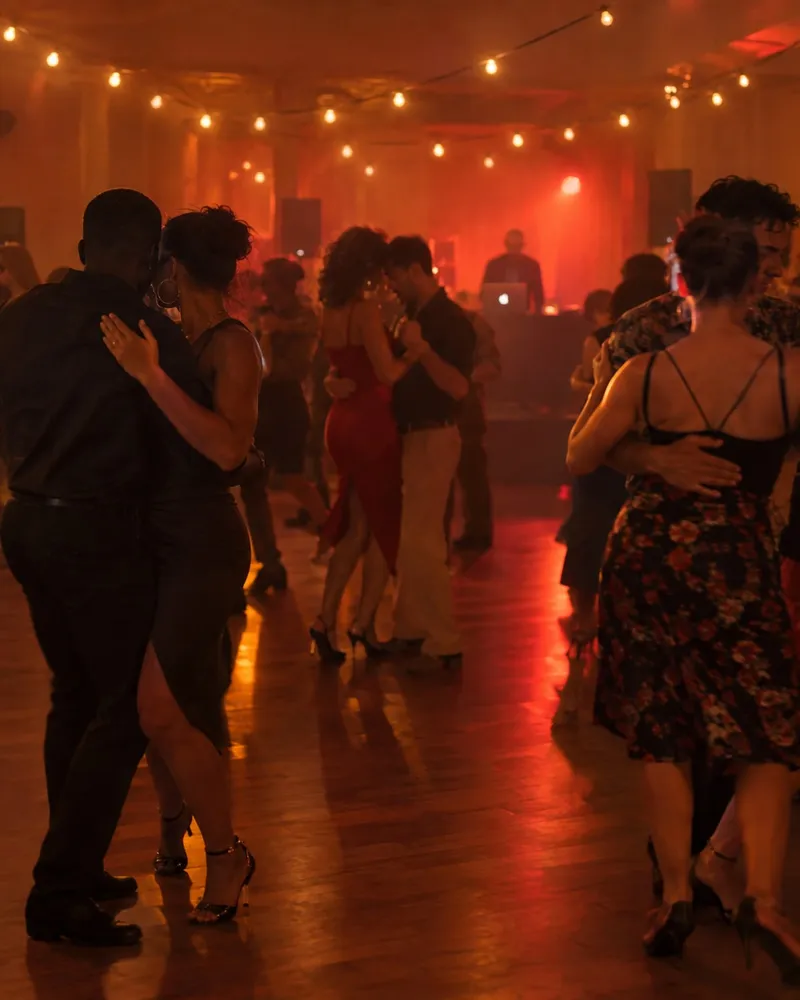 Casais a dançar numa festa de dança à noite, sob luzes quentes